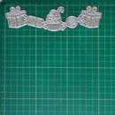 A set of silver metal cutting dies shaped like wrapped gifts, a cupcake, and a candy cane, arranged on a green gridded cutting mat.