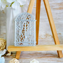 A decorative silver metal arch ornament with intricate filigree cutouts, displayed on a wooden easel stand.