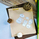 A kraft paper bag with a white line-art coffee-themed illustration, clipped at the top with a gold metal binder clip and arranged on a dark wood surface with decorative woven balls and a green stem.