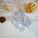 A floral metal cutting die set with daffodils and tulips, displayed on a light wood background with decorative woven balls.