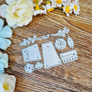 A set of metal die-cut craft templates for scrapbooking, featuring floral and geometric shapes, displayed on a rustic wooden surface with decorative white and blue flowers.