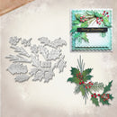 A holiday crafting set featuring a silver metal die-cutting and embossing machine blade set on the left, and a layered paper card example on the top right decorated with green holly leaves, red berries, and a black 'Merry Christmas' banner.