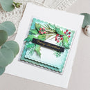 A handmade layered Christmas greeting card with scalloped edges, green holly leaves, red berries, and a black banner reading 'Merry Christmas' in gold script, styled on a white textured card with eucalyptus leaves around it.