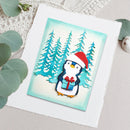 A square handmade greeting card featuring a cute penguin wearing a red Santa hat and holding a blue gift box, set against a snowy pine tree background. The card is displayed on a textured white cardstock sheet with decorative eucalyptus leaves around it.