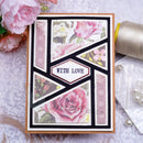 A handmade greeting card with a geometric design featuring pink roses and floral prints, bordered in black and white, with the words 'WITH LOVE' in the center. The card is styled on a patterned surface with pink flowers, a spool of thread, and pearls nearby.