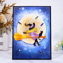 A square black-framed art print or card featuring a whimsical Halloween scene: a witch in a purple hat sits on a yellow-orange broomstick with a black cat beside it, set against a blue moonlit background with dots, stars, and small decorative embellishments.