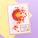 A handmade greeting card featuring a 3D layered red flower with a yellow center, scattered red and yellow hearts, and the text 'just for you' in a small white box, displayed on a yellow and purple background.