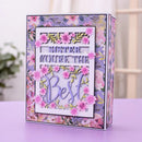 A decorative handmade greeting card or scrapbook box with floral patterns, featuring the text 'Sister You Are The Best' in layered white and purple paper cutouts, displayed on a lavender surface.