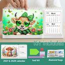 A tabletop display of a spring-themed diamond painting calendar kit, showing a hand holding the open spiral-bound 2026 calendar. The cover features a colorful beaded illustration of a brown bear wearing green sunglasses and a green bow, surrounded by flowers and butterflies.