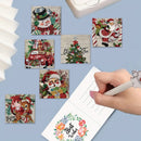 Six square Christmas-themed adhesive notes or stickers with vintage illustrations are displayed on a light blue background, alongside a hand writing on a lined card. The illustrations include Santa Claus, a snowman, a red car, a Christmas tree, and a deer.