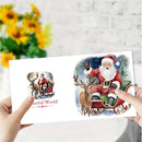 A person holds a white rectangular card featuring two Christmas illustrations: a small left print reading "Colorful World" and a larger right print of Santa Claus in a sleigh with a deer. The background shows a blurred white wall and yellow flowers.