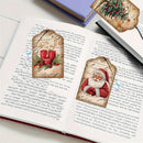 Two decorative paper bookmarks styled as rustic wood slices with red berries and pearl-like beads, placed on an open book with printed text. A small blue-and-white flower and a folded wood slice are also visible in the scene.