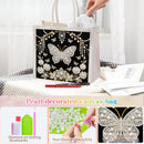 A pearl-decorated canvas bag with a black background and a large butterfly design made of white and gold rhinestones. The image shows a hand placing a card into the bag, with product feature callouts and close-up inset images at the bottom.