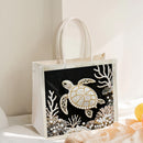 Decorative tote bag with a turtle design on a white surface