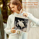 Woman holding a pearl-decorated canvas bag with a turtle design.