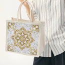Person holding a decorative tote bag with gold and white patterns