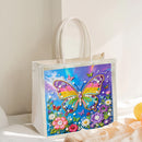 A clear plastic tote bag with white handles, featuring a colorful diamond painting design of a butterfly and flowers on the front, set against a softly lit neutral background.