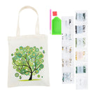 An off-white canvas tote bag with a green and black tree design, shown alongside a green paint palette, a pink paintbrush, and several small packets of decorative glitter or sequins on a white background.