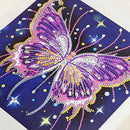 A square diamond painting or rhinestone art panel featuring a large butterfly design in purple, pink, and white on a dark blue background with star and bead details.