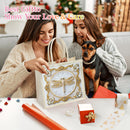 Two women and a small black-and-tan dog are gathered around a decorative gift bag on a table. The bag is cream with ornate gold trim and a large dragonfly motif in the center.