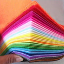 Stack of colorful felt sheets held by a hand against a neutral background