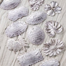 Decorative silver patches with floral and leaf designs on a textured fabric background