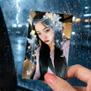 Person holding a photo of a woman with decorative elements against a rainy window background