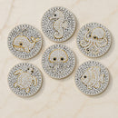 Six round, heavily embellished jewelry pieces arranged on a light marble surface. Each piece features a white base covered in small clear stones, with gold outlines and details forming sea creatures including a seahorse, octopus, crab, fish, and another sea life figure.
