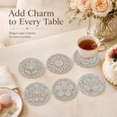 Six round pearl-bead coasters with floral and geometric patterns are arranged on a beige table alongside a teacup, cake, macarons, and flowers. Text on the image reads 'Add Charm to Every Table' and 'Elegant pearl coasters for every occasion.