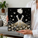 Person holding a decorative wall art piece with a woman in a dress and pearl headpiece.