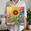 Person holding a colorful diamond painting of a sunflower and flowers