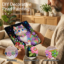 Person holding a DIY decorative pearl painting kit with a colorful cat design, set against a cozy living room background.