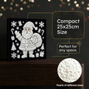 A black square decorative canvas or box featuring a white dotted Santa Claus design with snowflakes, gifts, and holiday motifs, displayed on a dark wooden surface. Text on the image states 'Compact 25x25cm Size' and 'Perfect for any space,' with a circular inset showing white pearl-like embellishments.