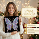 A woman in a white knit sweater holds a black square canvas featuring a colorful diamond painting butterfly with purple, blue, pink, and gold details. The background shows warm holiday lights and a decorated Christmas tree, with text overlays reading 'Perfect Holiday Gift' and 'Unique Pearl Art', 'Festive Decor', and 'Ready to Hang'.
