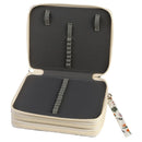 An open zippered jewelry organizer case with a cream-colored exterior and dark gray interior. The case features elastic loops and a central strap on the inside lid, and a floral-patterned wristlet strap is attached on the right side, all shown against a plain white background.