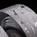 Roll of glittery black and silver decorative paper with star designs on a black background.