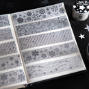 Set of silver washi tape rolls with various patterns on a black surface.