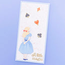 A vertical rectangular card featuring a layered paper cutout of a young girl in a light blue dress with blonde hair, standing with hands behind her back. The card is decorated with floating playing card suits (spade, heart, diamond, club) in gold, orange, and dark gray, with the gold text 'A little magic' at the bottom.