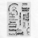 A clear rectangular stamp sheet featuring multiple black printed phrases and decorative text elements such as 'YOU', 'Sweet as HONEY', 'Magic INSIDE', 'You are blooming amazing!', and 'Sending love You're sweet'.