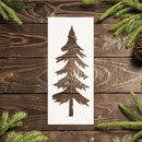 Wooden stenciled tree design on a wooden surface with pine branches and cones.
