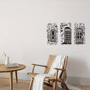 Three black vinyl wall decals depicting London-themed storefronts are displayed on a light beige wall in a styled room setting with a wooden chair, side table, and white throw blanket.