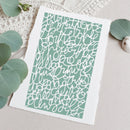 A square art print with a white border and a mint green background featuring an abstract white line pattern, styled flat-lay on a neutral fabric with eucalyptus leaves.