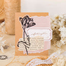 A handmade vintage-style greeting card with torn paper elements, featuring a black tulip illustration and a decorative label, styled on a neutral background with dried flowers and twine.