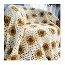 A crocheted sunflower-pattern throw blanket draped over an armchair in a bright indoor setting. The blanket features cream-colored crochet borders with yellow and brown sunflower motifs.