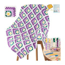 A crocheted blanket with a repeating granny square pattern in purple, white, and green is draped over a wooden stool. The image includes a small inset showing the finished square motif, a materials stack with yarn, tools, and a phone photo, and a white background.