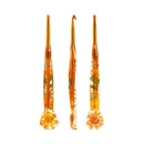 Three amber glass crochet hooks with embedded dried flowers and leaves, displayed on a solid white background.
