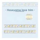 A square product card for 'Haseyama lace trim' by crochet tales, showing a light blue background with two horizontal strips of floral lace trim and a circular logo badge.