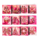 A set of 12 Christmas-themed greeting cards arranged in a 3x4 grid, featuring festive illustrations like bells, a candle, a gift box, a star, a mug of hot chocolate, knit mittens, a snowflake, a stocking, a wreath, a Christmas tree, and a candy cane, all in a pink and gold color scheme.