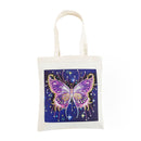 An off-white canvas tote bag with a square graphic print of a glittery purple and pink butterfly on a dark blue starry background.