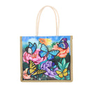 A canvas tote bag with a colorful printed design of blue butterflies, pink and purple flowers, and green leaves on a light blue background. The bag has a natural beige woven border and two cream-colored shoulder straps, shown against a plain white background.